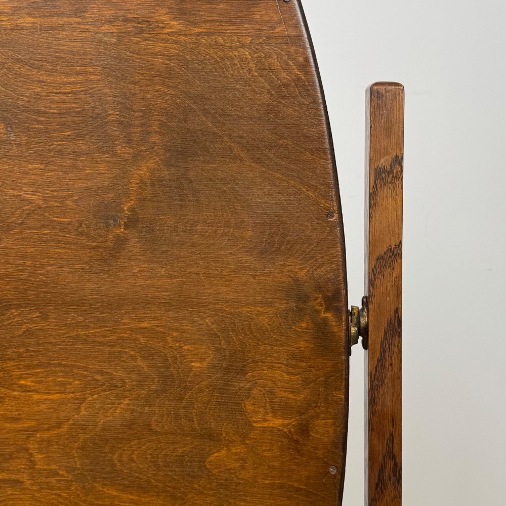 An Edwardian oak cheval mirror featuring an oval glass frame suspended between two upright posts on trestle feet. View XIII