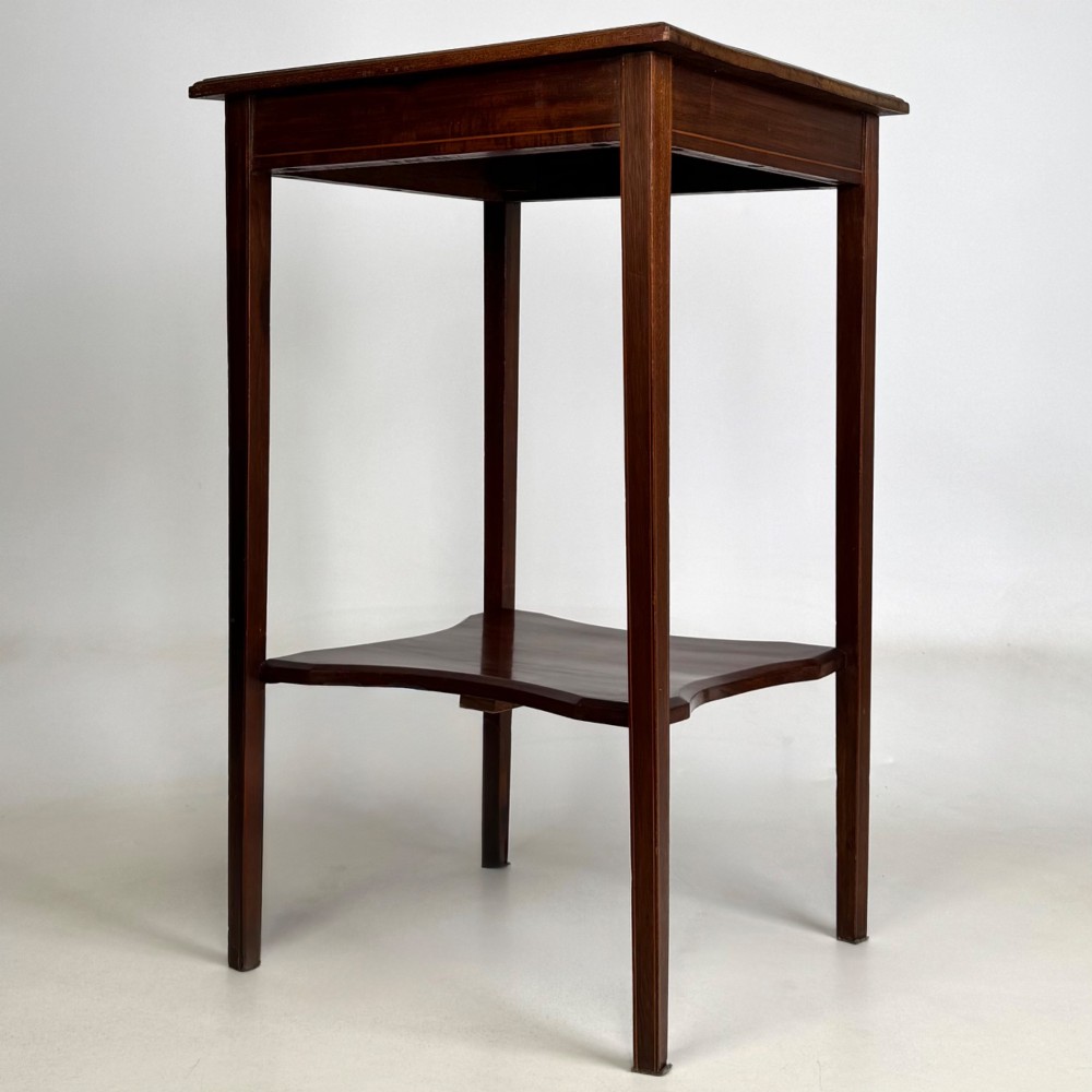 A tall Edwardian mahogany side table featuring four slender tapered legs, a square top surface, and a concave-shaped lower undertier. View II