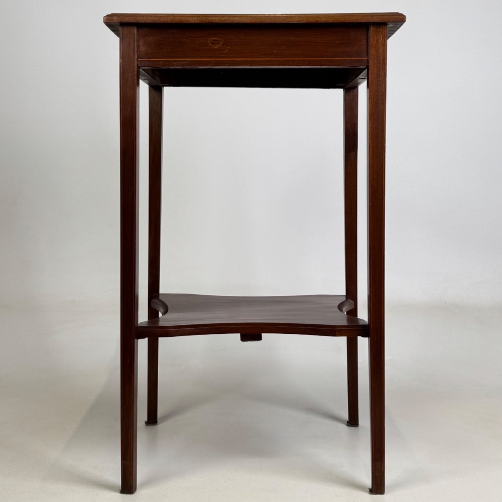 A tall Edwardian mahogany side table featuring four slender tapered legs, a square top surface, and a concave-shaped lower undertier. View V