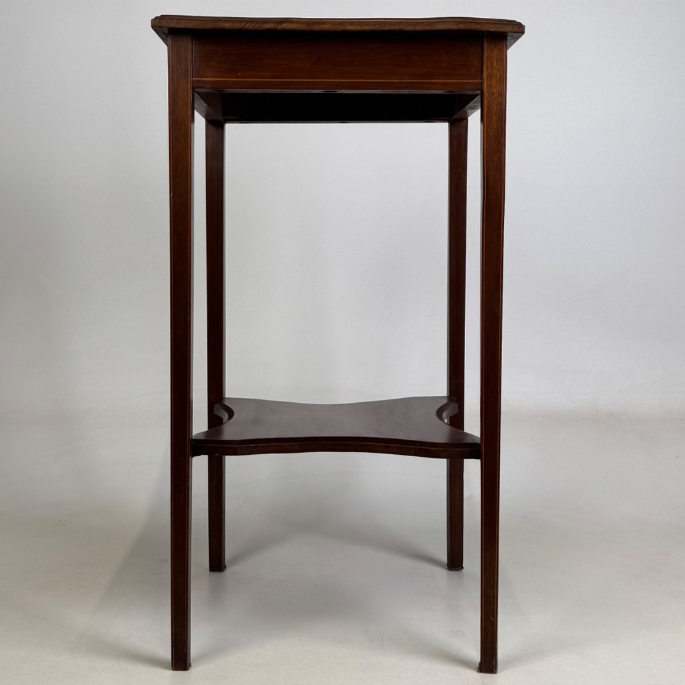 A tall Edwardian mahogany side table featuring four slender tapered legs, a square top surface, and a concave-shaped lower undertier. View VII