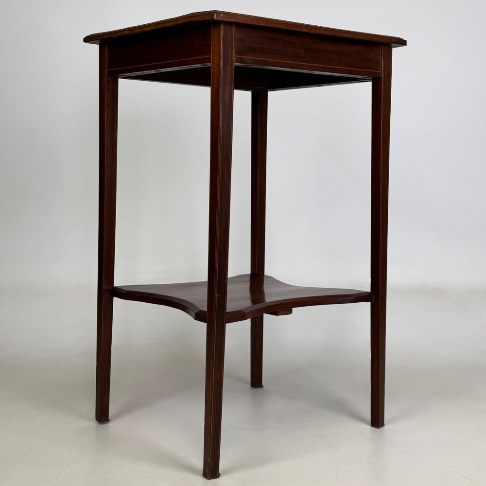 A tall Edwardian mahogany side table featuring four slender tapered legs, a square top surface, and a concave-shaped lower undertier. View VIII