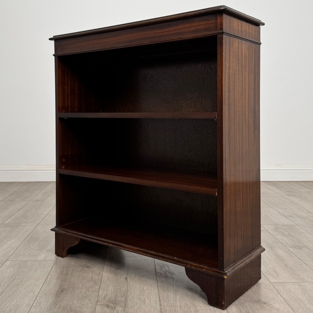 An Edwardian dark mahogany low open bookcase with three shelves and a moulded top. View III