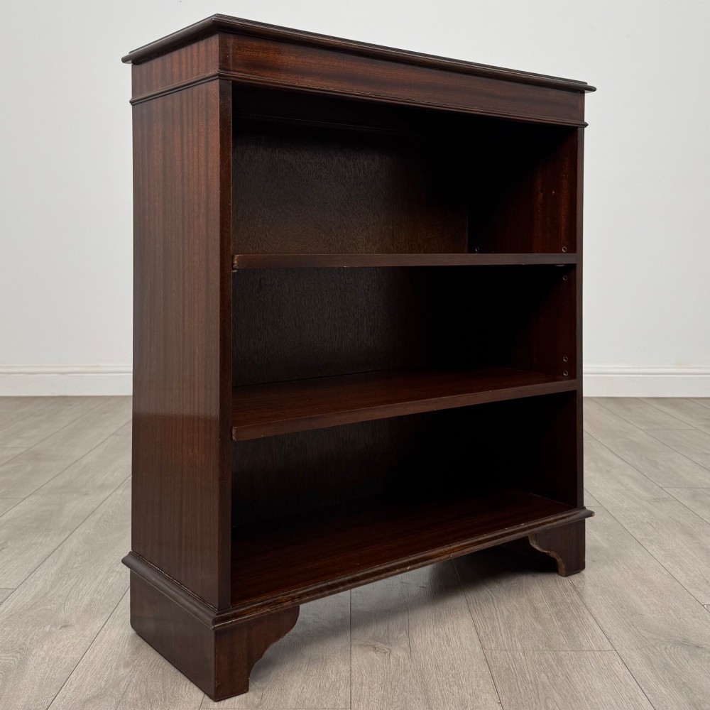 An Edwardian dark mahogany low open bookcase with three shelves and a moulded top. View IX