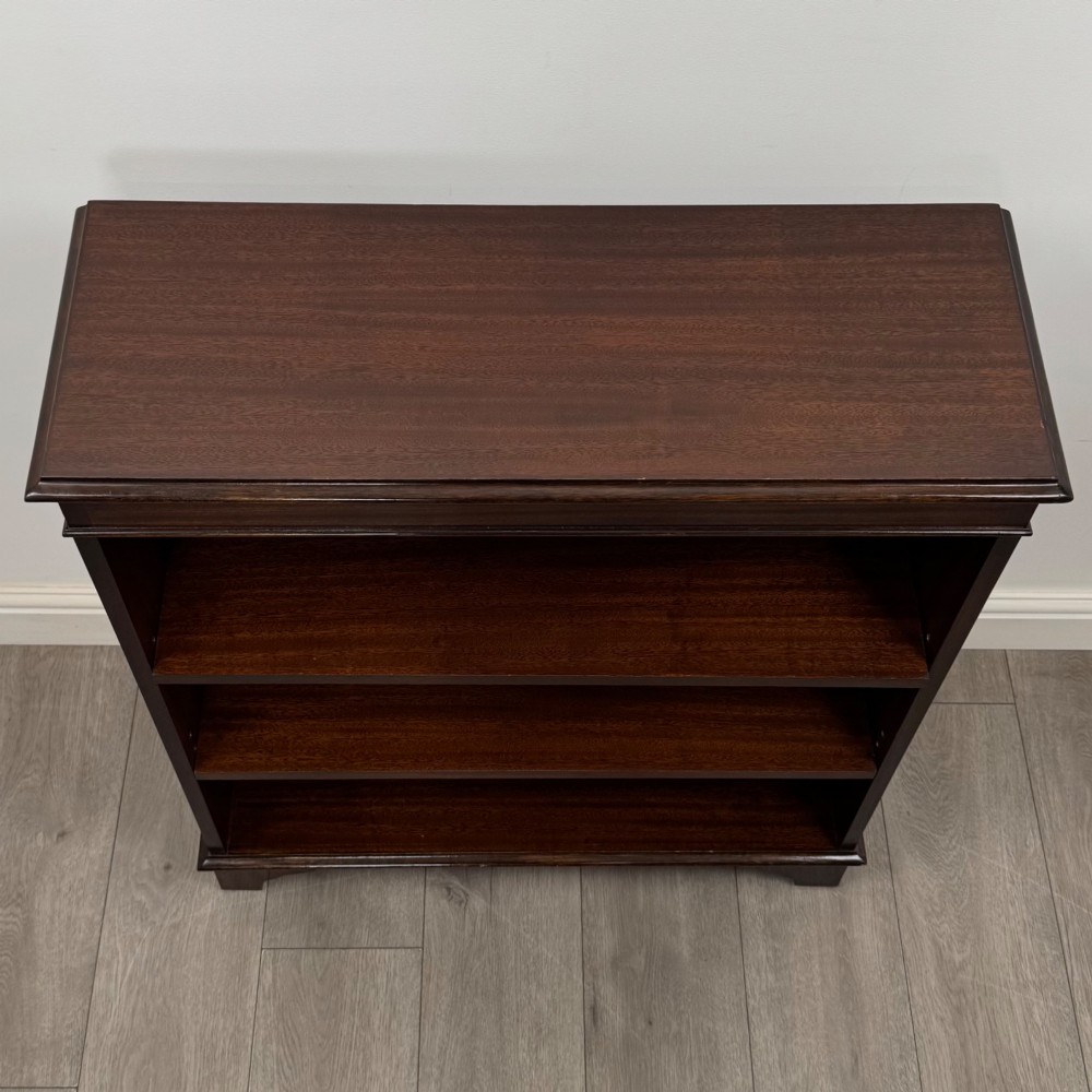 An Edwardian dark mahogany low open bookcase with three shelves and a moulded top. View X