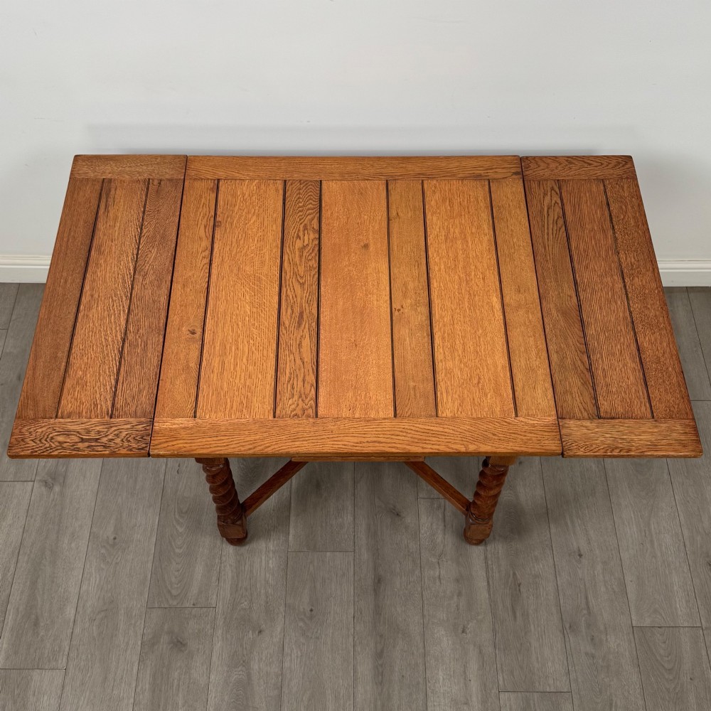 An Edwardian warm oak draw leaf dining table featuring extended side leaves, barley twist legs, and an X-frame cross stretcher. View V