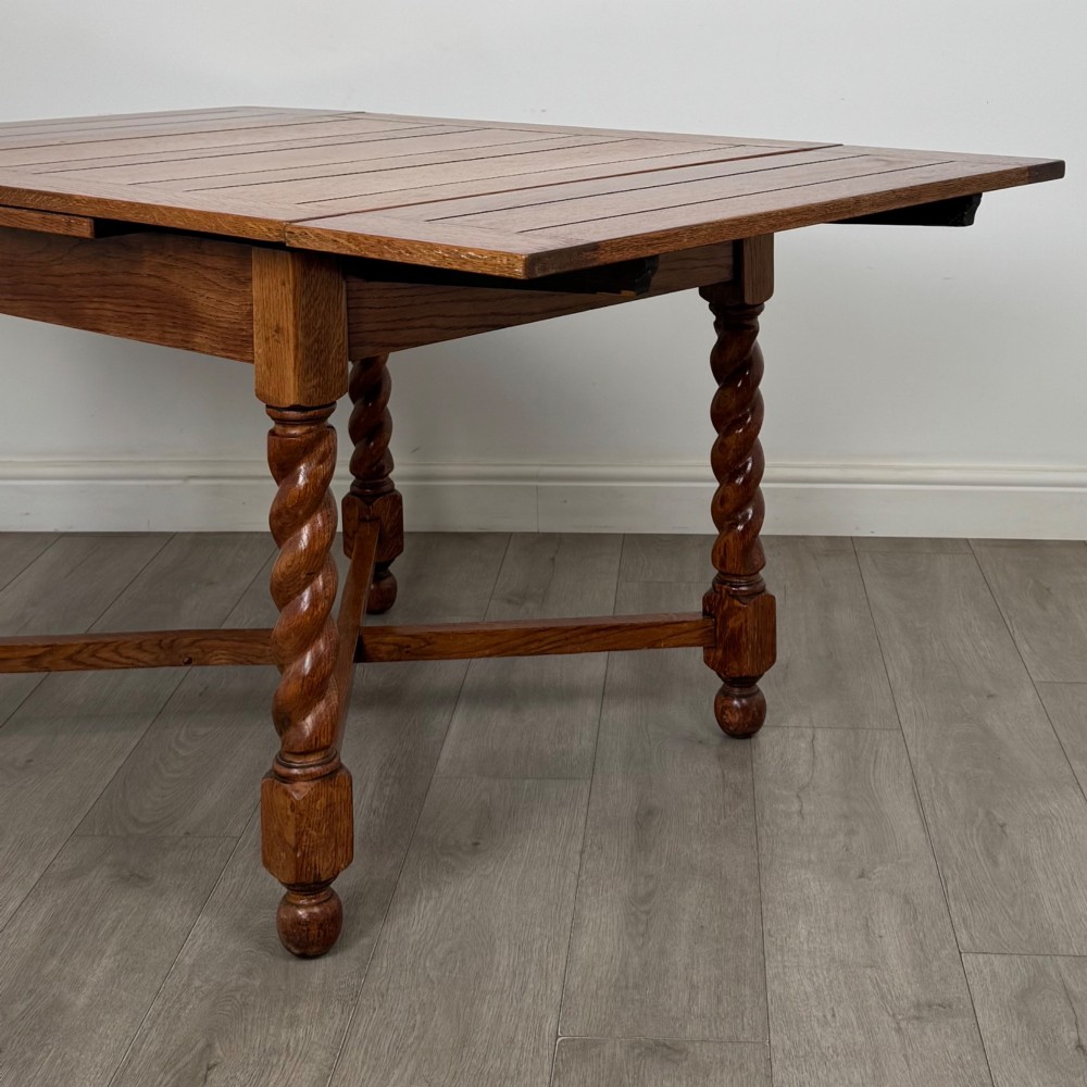 An Edwardian warm oak draw leaf dining table featuring extended side leaves, barley twist legs, and an X-frame cross stretcher. View VI