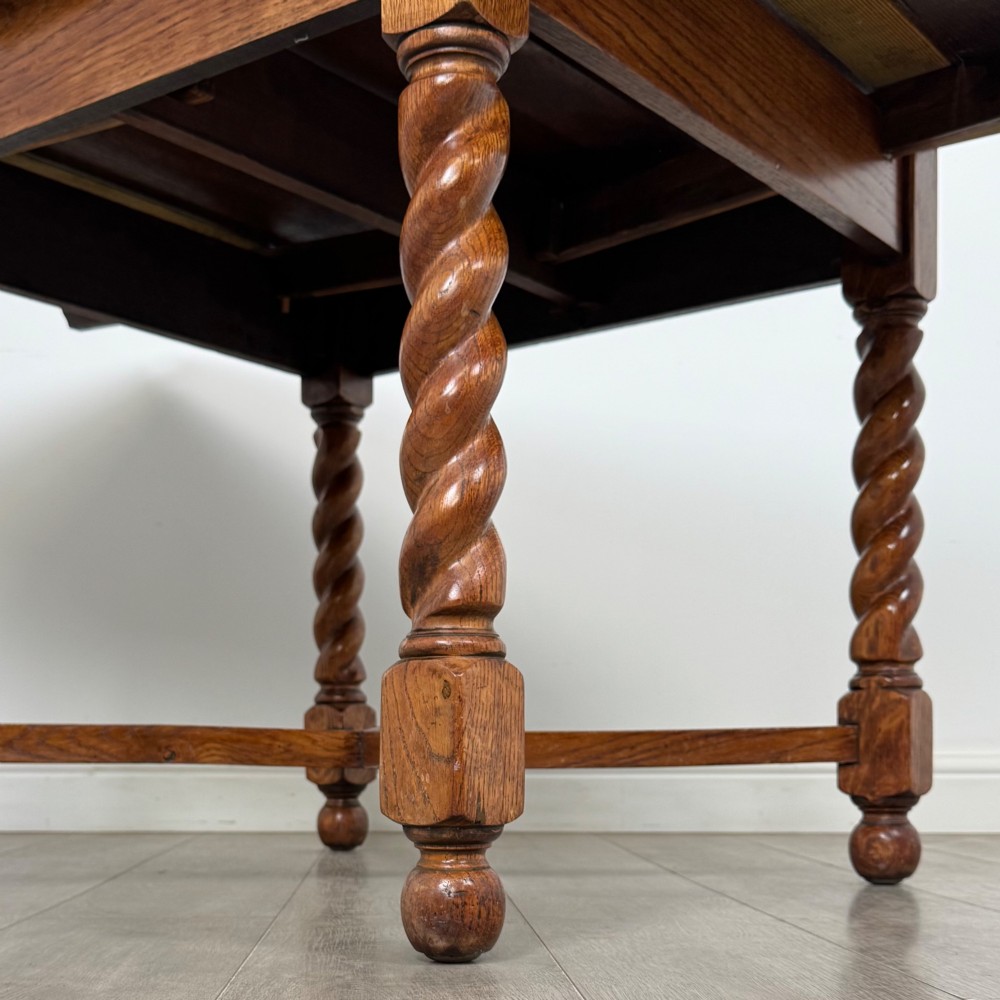 An Edwardian warm oak draw leaf dining table featuring extended side leaves, barley twist legs, and an X-frame cross stretcher. View VII