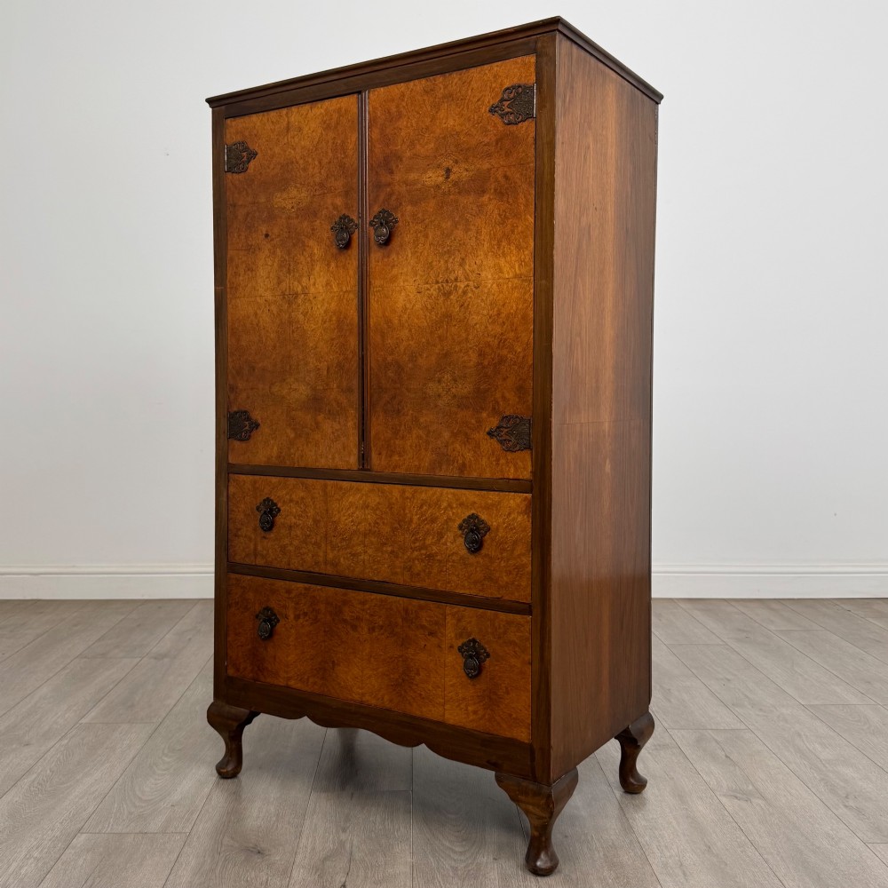 An Edwardian burr walnut storage cupboard featuring two top doors with brass strap hinges above two drawers on cabriole legs. View III
