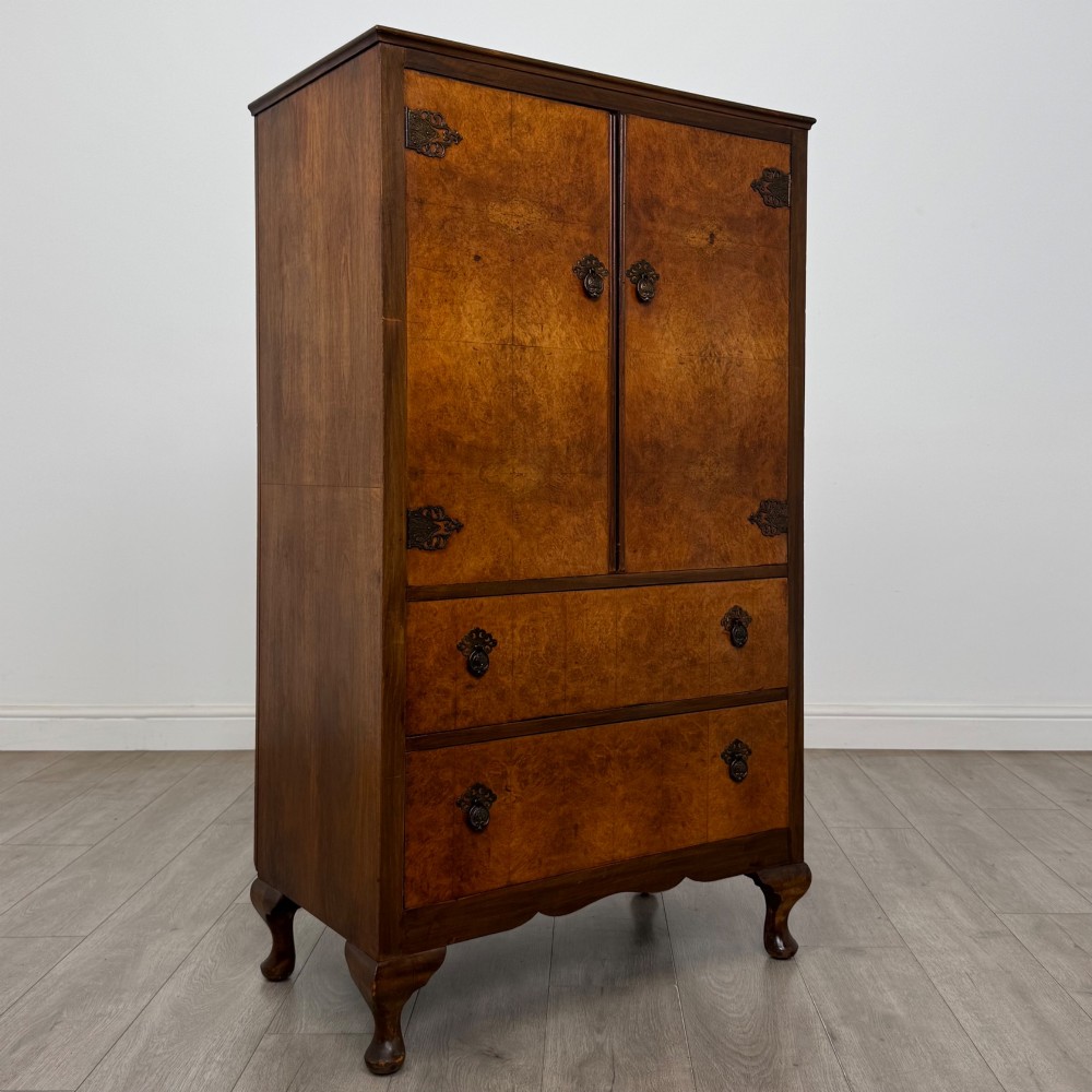 An Edwardian burr walnut storage cupboard featuring two top doors with brass strap hinges above two drawers on cabriole legs. View IX