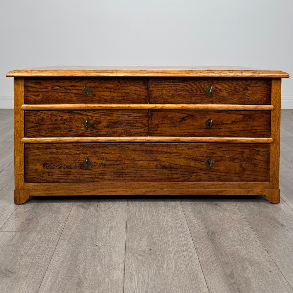 A low 20th-century oak chest of drawers featuring five drawers arranged across three tiers with diamond-shaped metal handles.