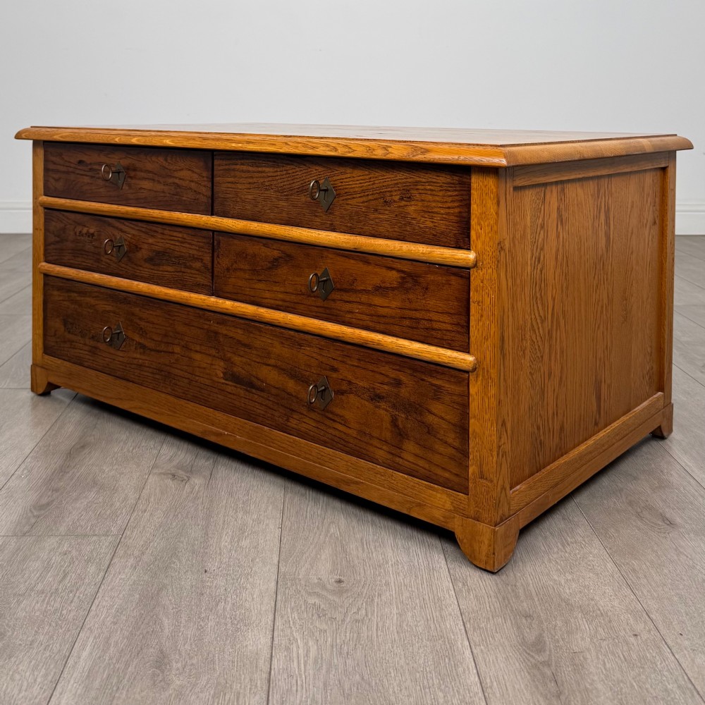A low 20th-century oak chest of drawers featuring five drawers arranged across three tiers with diamond-shaped metal handles. View II