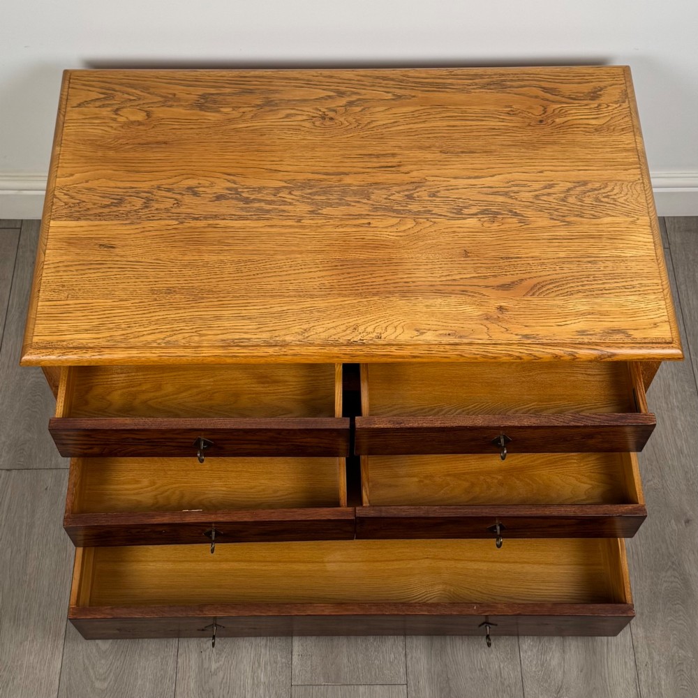 A low 20th-century oak chest of drawers featuring five drawers arranged across three tiers with diamond-shaped metal handles. View X