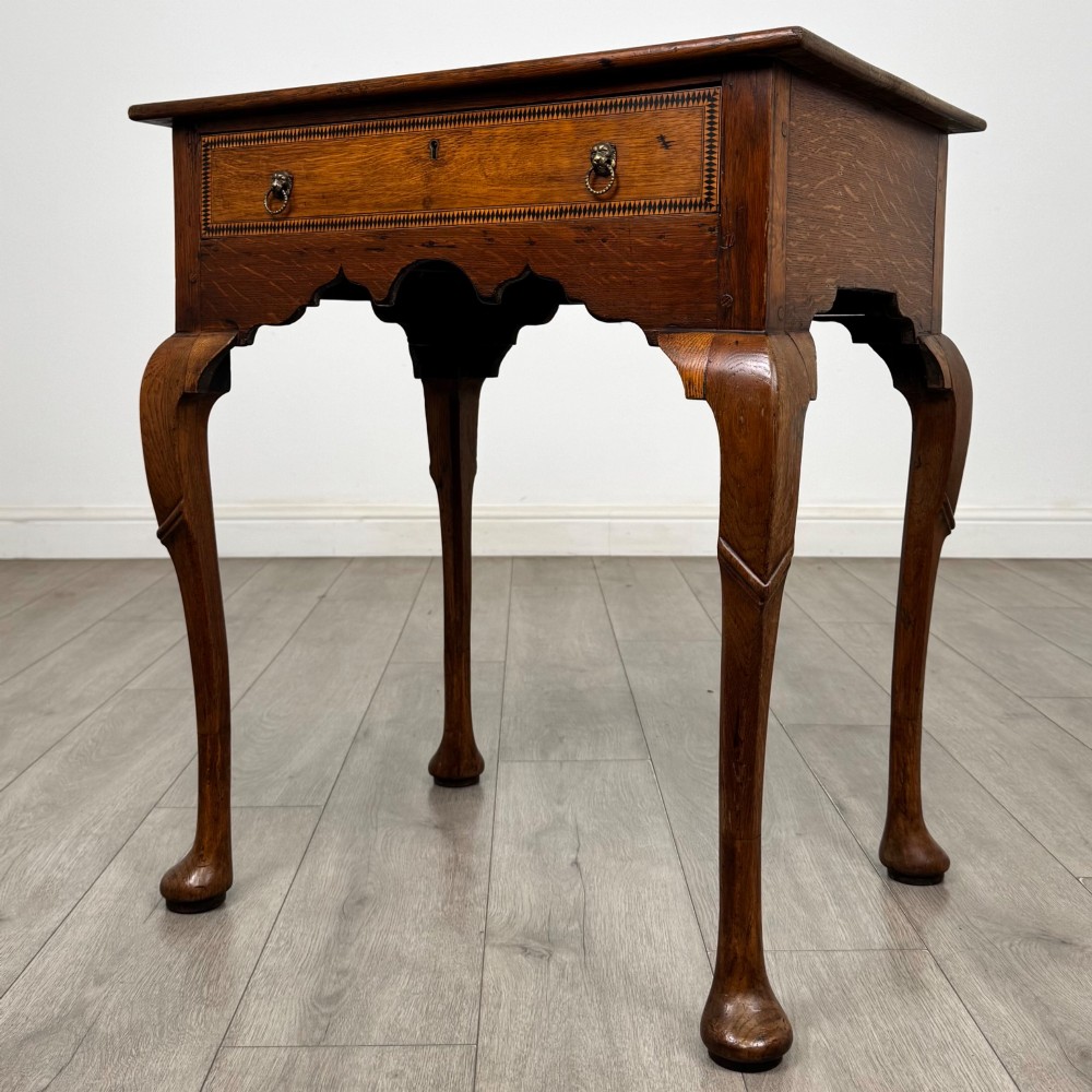 An 18th-century Georgian oak side table featuring a single drawer with geometric inlaid border, lion mask brass ring handles, shaped apron, and four cabriole legs ending in pad feet. View II