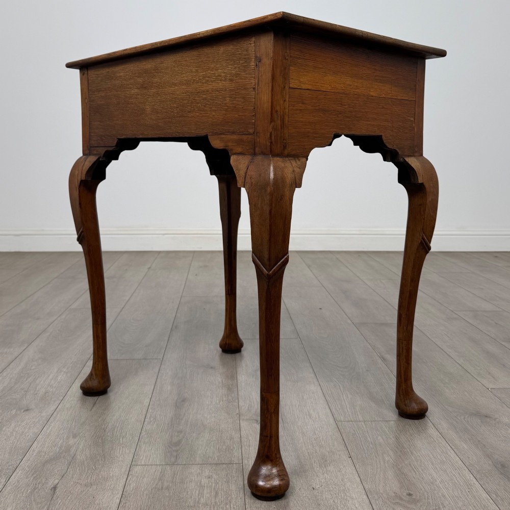 An 18th-century Georgian oak side table featuring a single drawer with geometric inlaid border, lion mask brass ring handles, shaped apron, and four cabriole legs ending in pad feet. View VI
