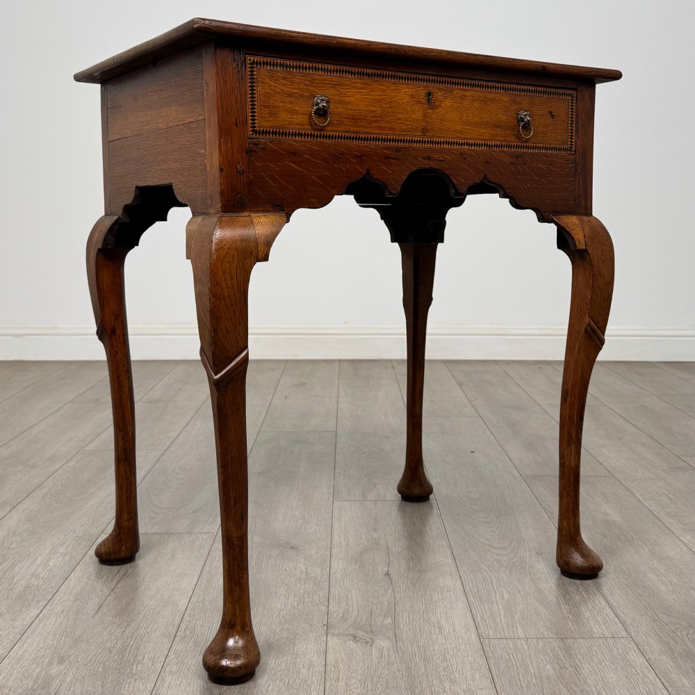 An 18th-century Georgian oak side table featuring a single drawer with geometric inlaid border, lion mask brass ring handles, shaped apron, and four cabriole legs ending in pad feet. View VIII