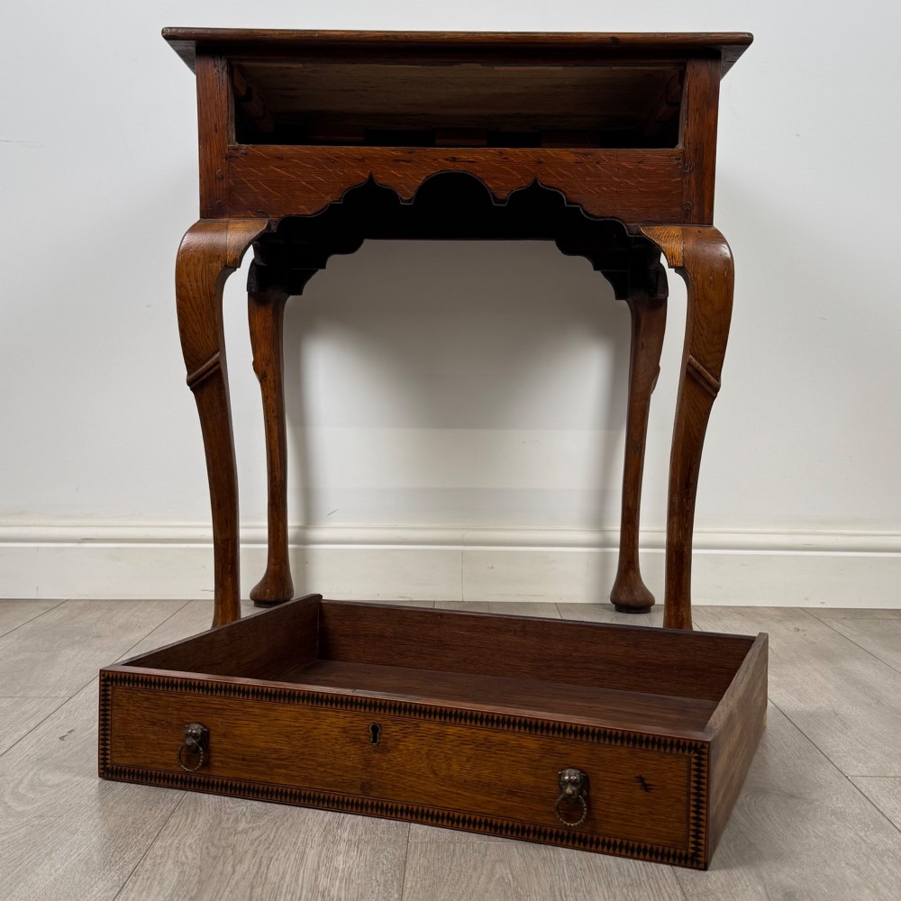 An 18th-century Georgian oak side table featuring a single drawer with geometric inlaid border, lion mask brass ring handles, shaped apron, and four cabriole legs ending in pad feet. View X