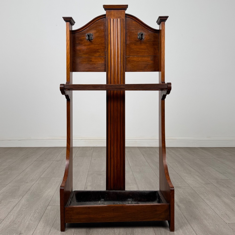 An Edwardian walnut hall stand featuring a fluted central column, metal coat hooks, a horizontal umbrella rail, and a metal drip tray at the base.