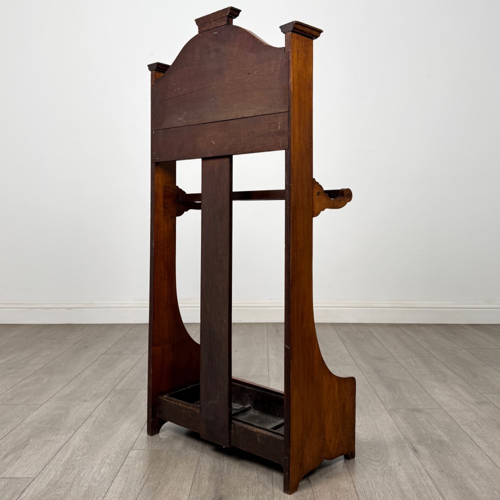 An Edwardian walnut hall stand featuring a fluted central column, metal coat hooks, a horizontal umbrella rail, and a metal drip tray at the base. View VI