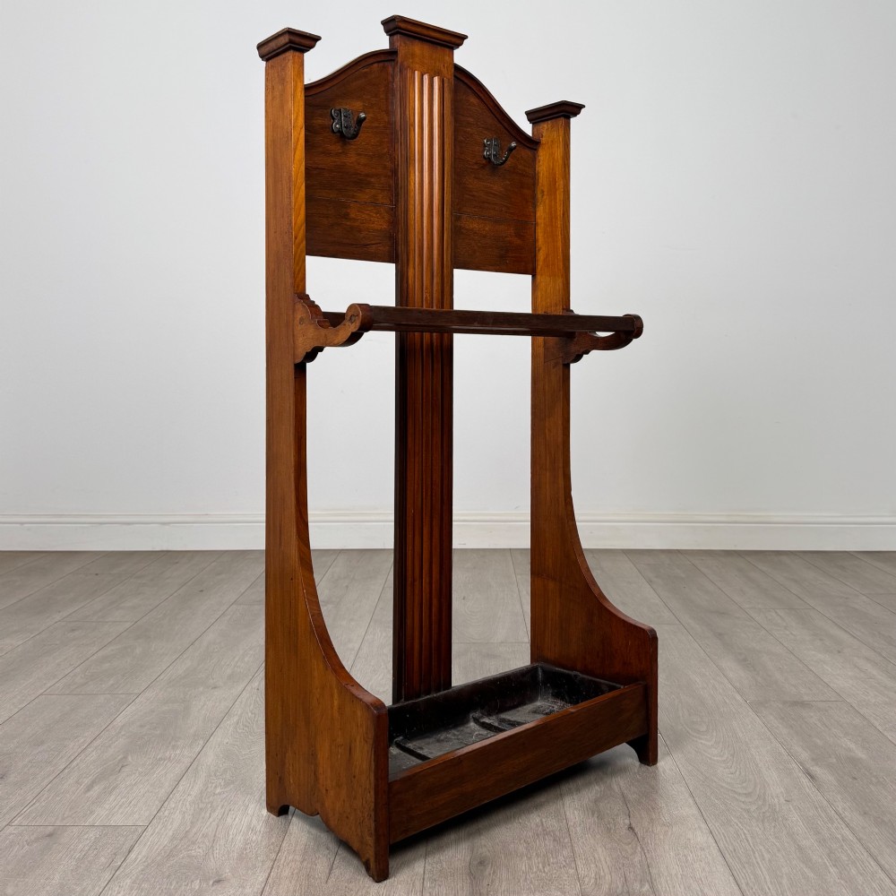 An Edwardian walnut hall stand featuring a fluted central column, metal coat hooks, a horizontal umbrella rail, and a metal drip tray at the base. View VIII