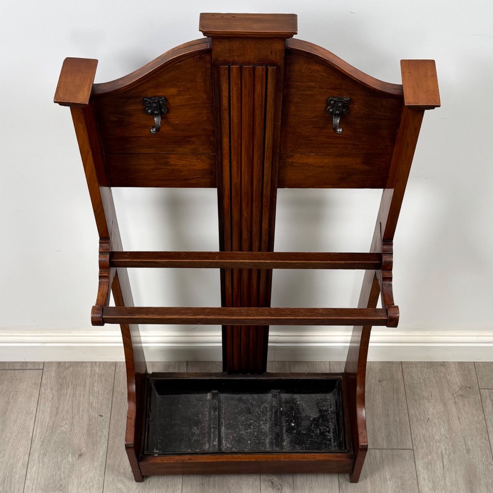 An Edwardian walnut hall stand featuring a fluted central column, metal coat hooks, a horizontal umbrella rail, and a metal drip tray at the base. View IX