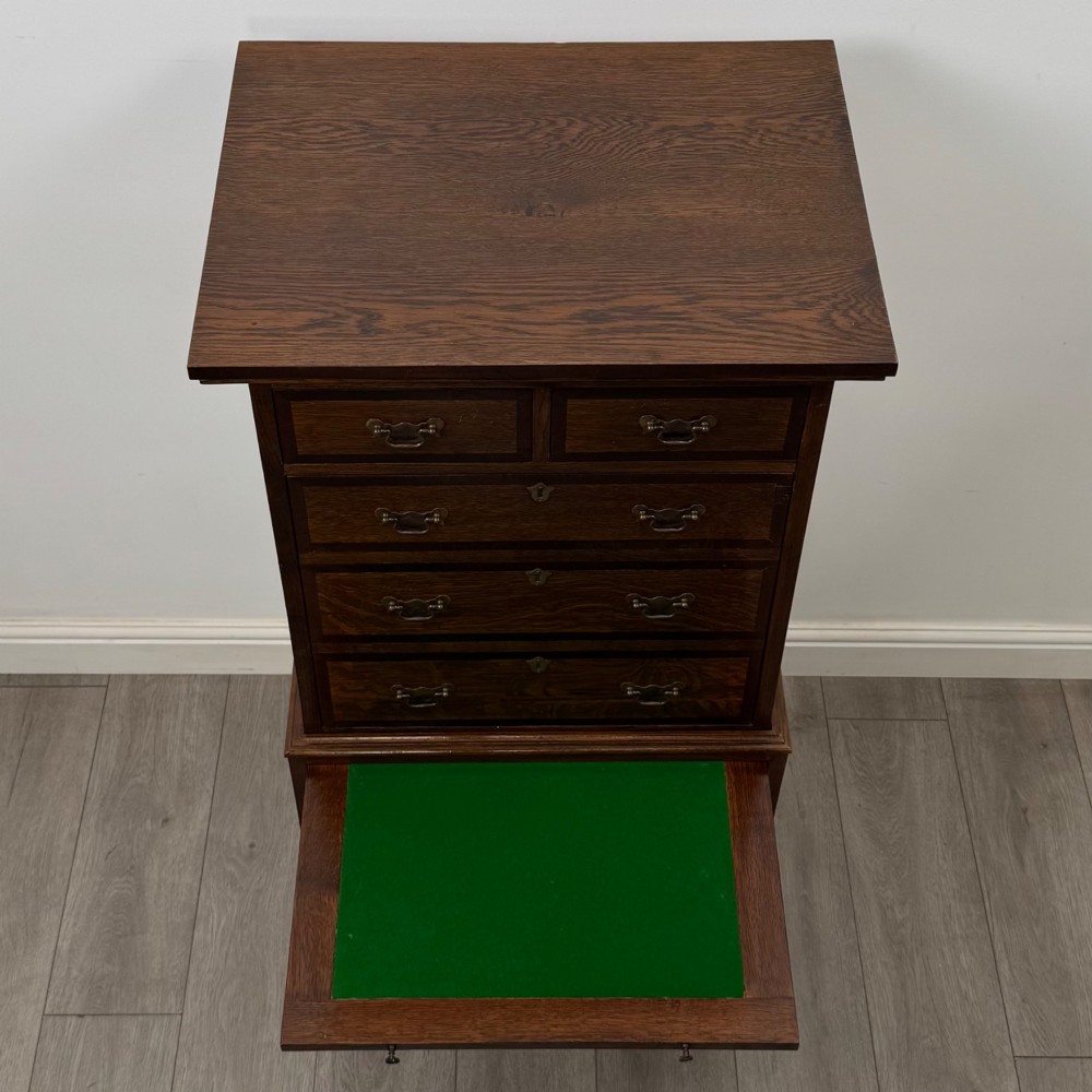 A tall early 20th-century oak chest on chest featuring multiple drawers with crossbanded borders and brass drop handles set on bracket feet. View XI