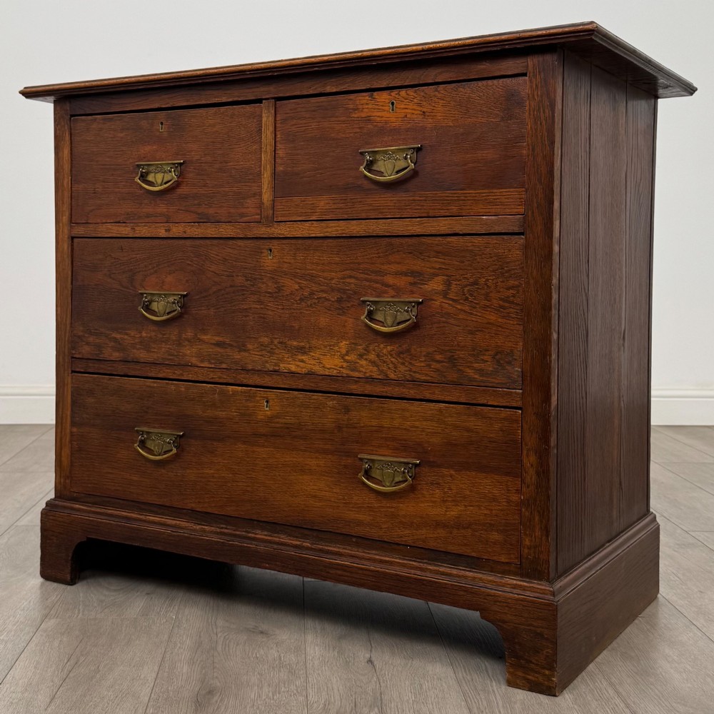 An antique Edwardian dark oak chest of drawers featuring two small top drawers above two full-width drawers with brass handles. View II