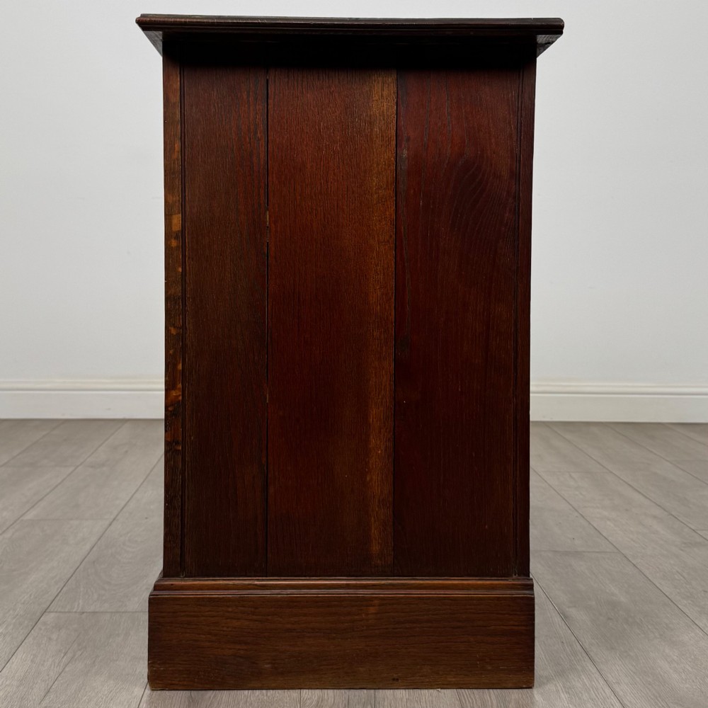 An antique Edwardian dark oak chest of drawers featuring two small top drawers above two full-width drawers with brass handles. View III