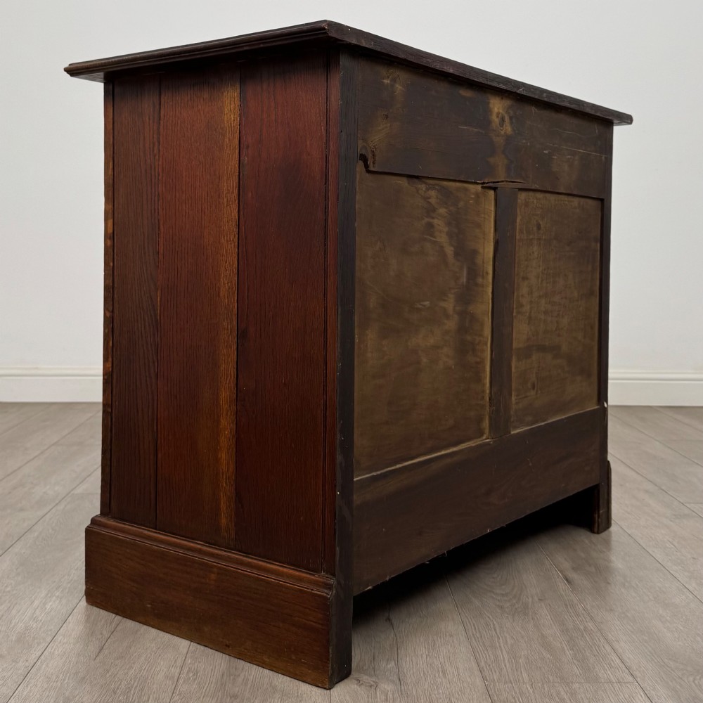 An antique Edwardian dark oak chest of drawers featuring two small top drawers above two full-width drawers with brass handles. View IV