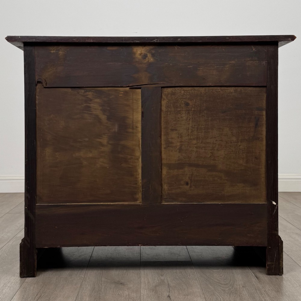 An antique Edwardian dark oak chest of drawers featuring two small top drawers above two full-width drawers with brass handles. View V