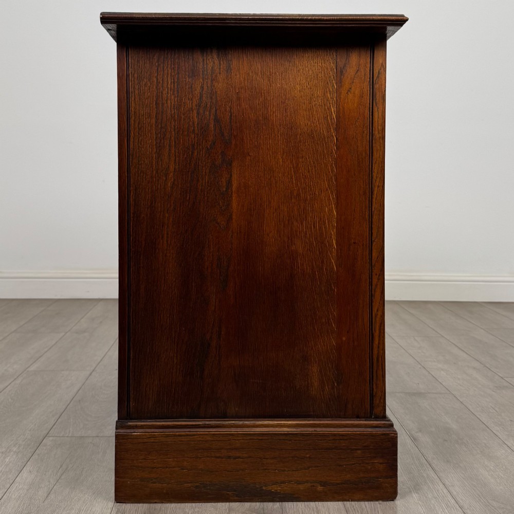 An antique Edwardian dark oak chest of drawers featuring two small top drawers above two full-width drawers with brass handles. View VII
