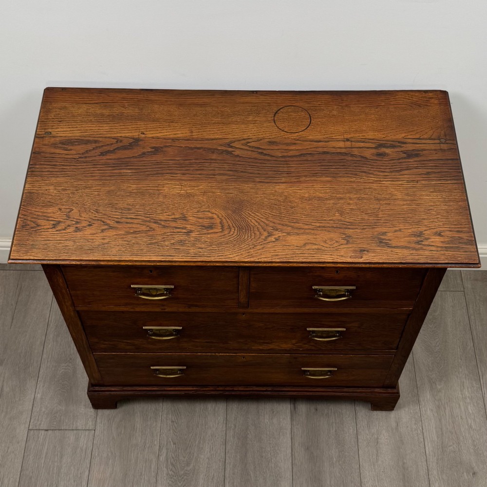 An antique Edwardian dark oak chest of drawers featuring two small top drawers above two full-width drawers with brass handles. View IX