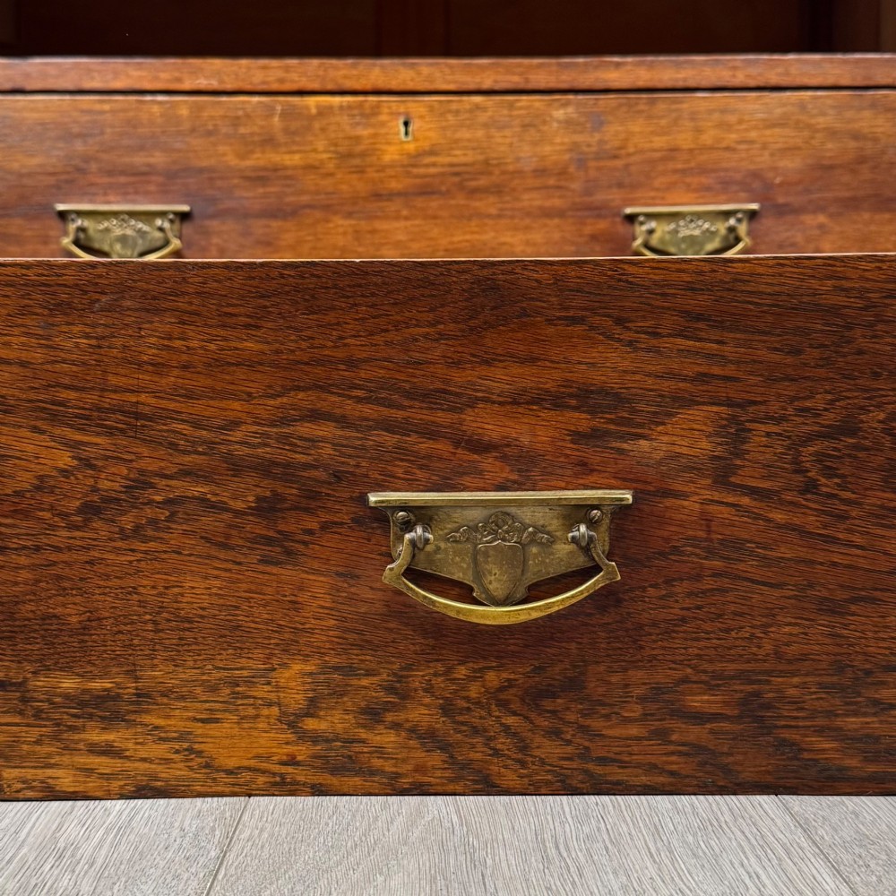 An antique Edwardian dark oak chest of drawers featuring two small top drawers above two full-width drawers with brass handles. View XI