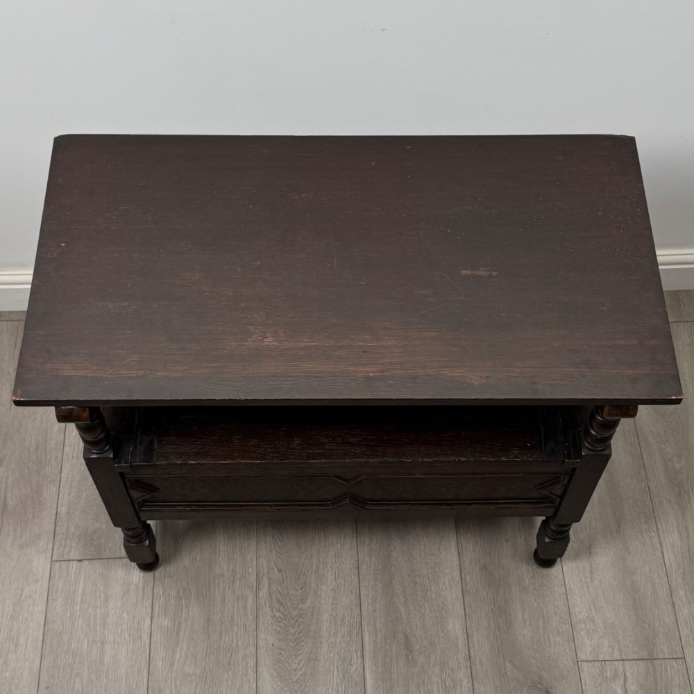 A dark oak monks bench featuring a panelled backrest with a central diamond motif, turned arm supports, and a lift-up seat. View XII