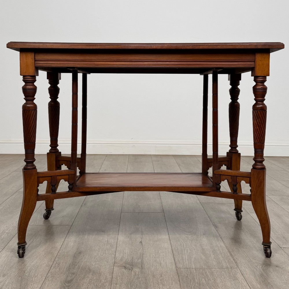 An Edwardian walnut side table featuring turned spiral legs, a lower shelf, carved corner brackets, and metal castors. View V