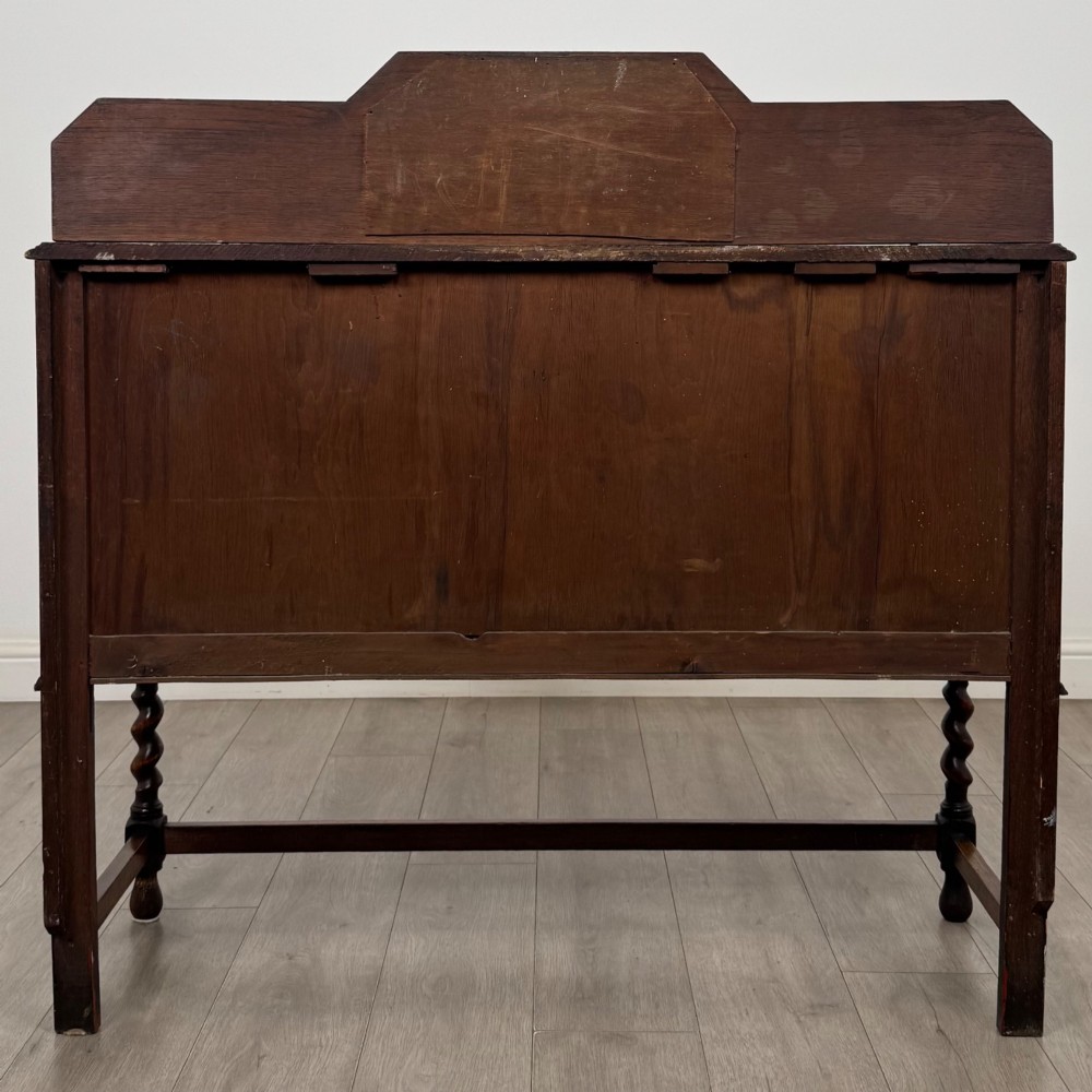 An Edwardian golden oak sideboard featuring a raised mirror back gallery, two drawers, two cabinet doors with geometric mouldings, and barley twist front legs. View VI