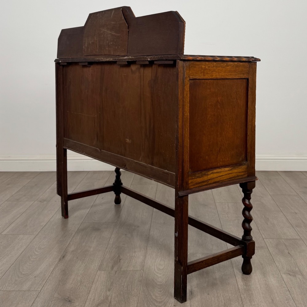 An Edwardian golden oak sideboard featuring a raised mirror back gallery, two drawers, two cabinet doors with geometric mouldings, and barley twist front legs. View VII