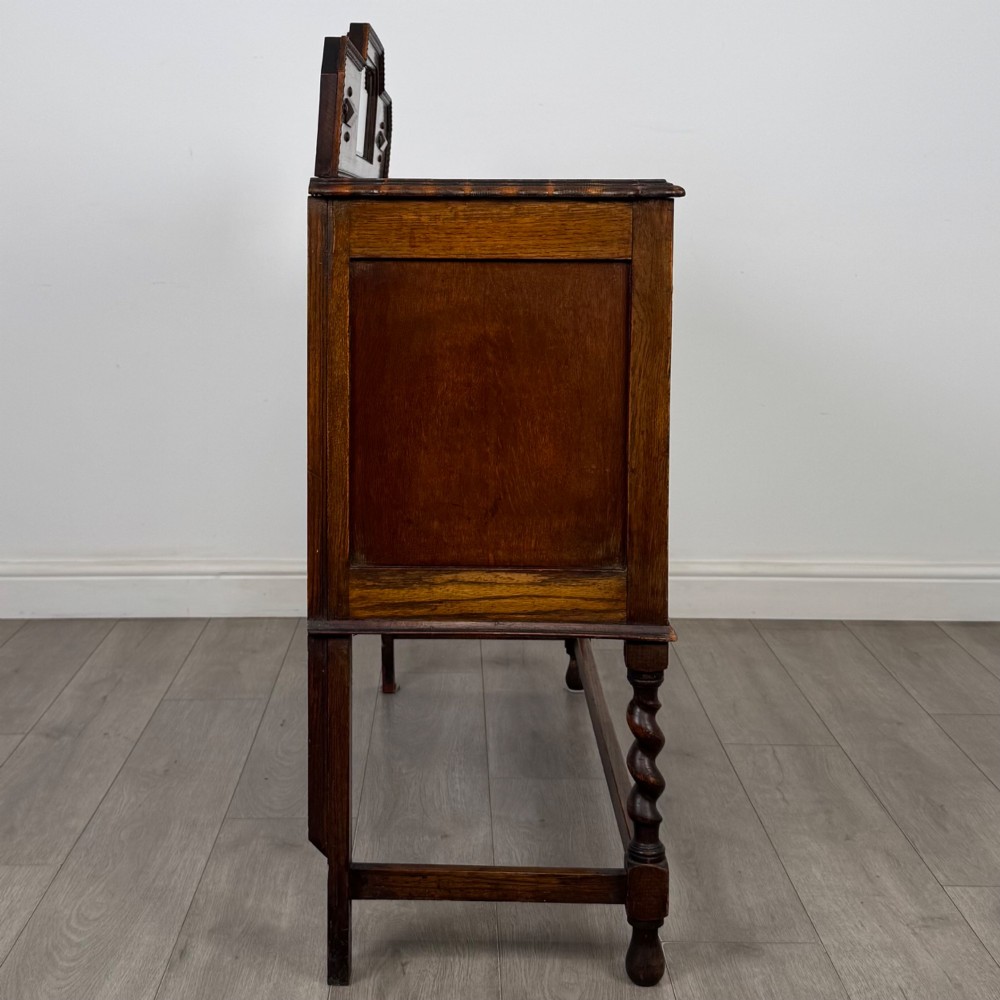 An Edwardian golden oak sideboard featuring a raised mirror back gallery, two drawers, two cabinet doors with geometric mouldings, and barley twist front legs. View VIII