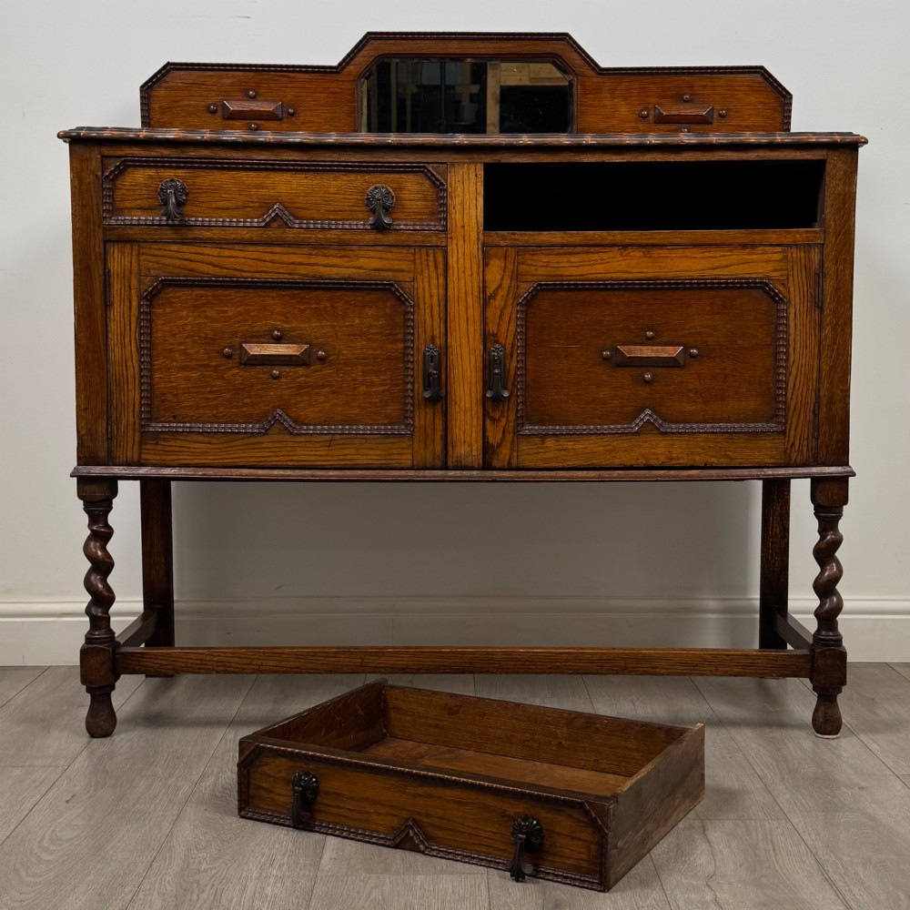 An Edwardian golden oak sideboard featuring a raised mirror back gallery, two drawers, two cabinet doors with geometric mouldings, and barley twist front legs. View XI