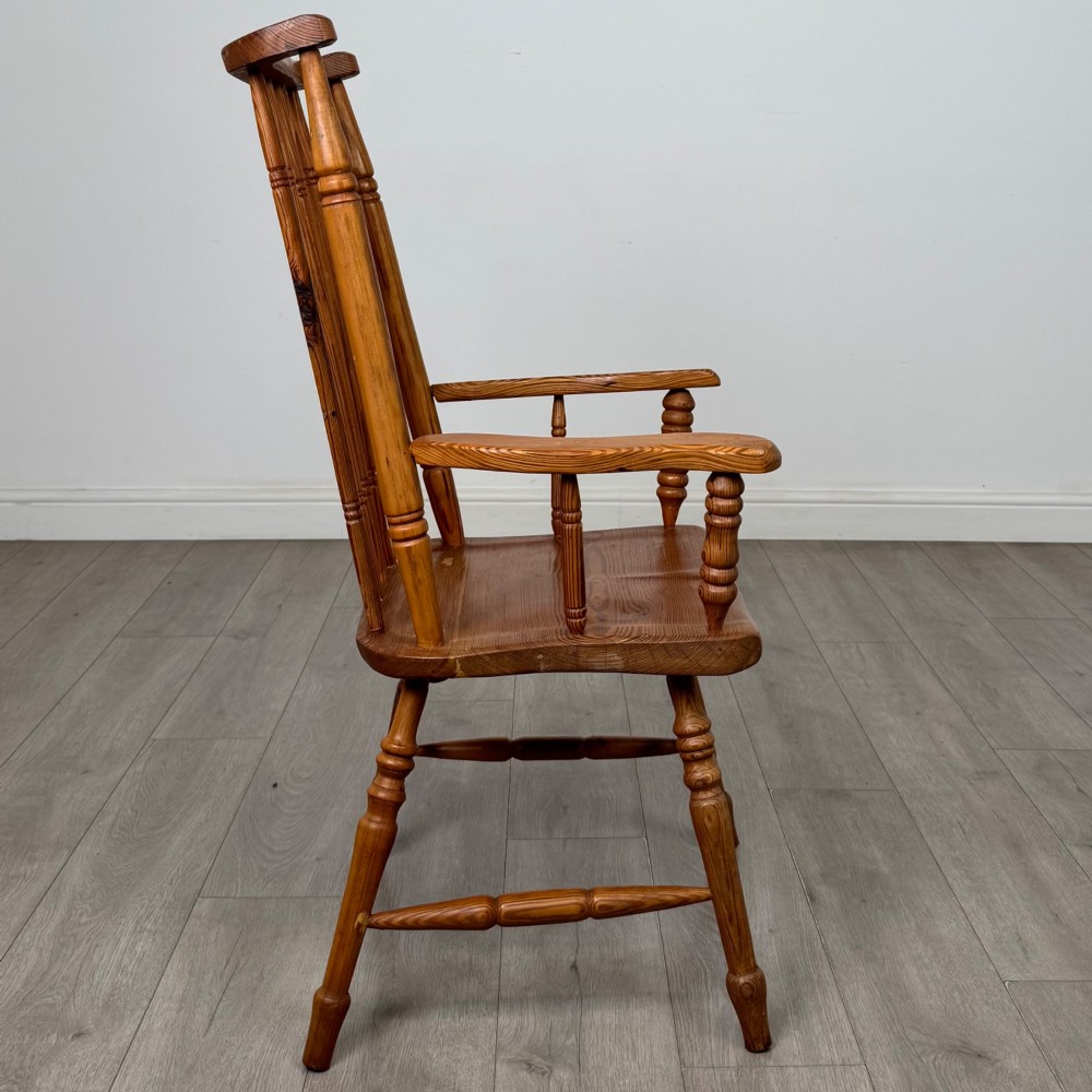 A twentieth-century pitch pine armchair featuring a tall stick back, sculpted armrests, and turned legs joined by stretchers. View VI