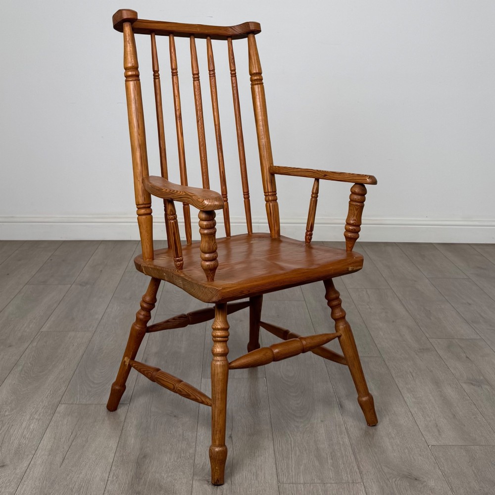 A twentieth-century pitch pine armchair featuring a tall stick back, sculpted armrests, and turned legs joined by stretchers. View VII