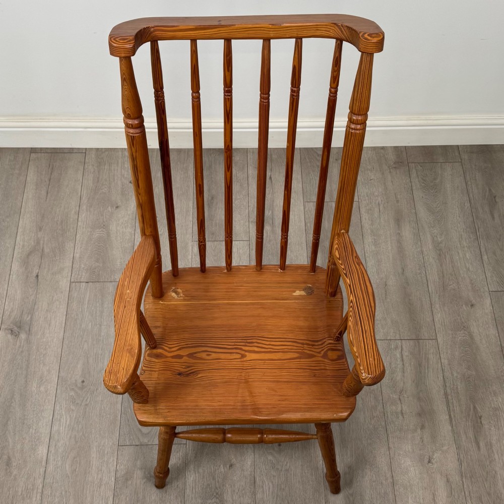 A twentieth-century pitch pine armchair featuring a tall stick back, sculpted armrests, and turned legs joined by stretchers. View IX
