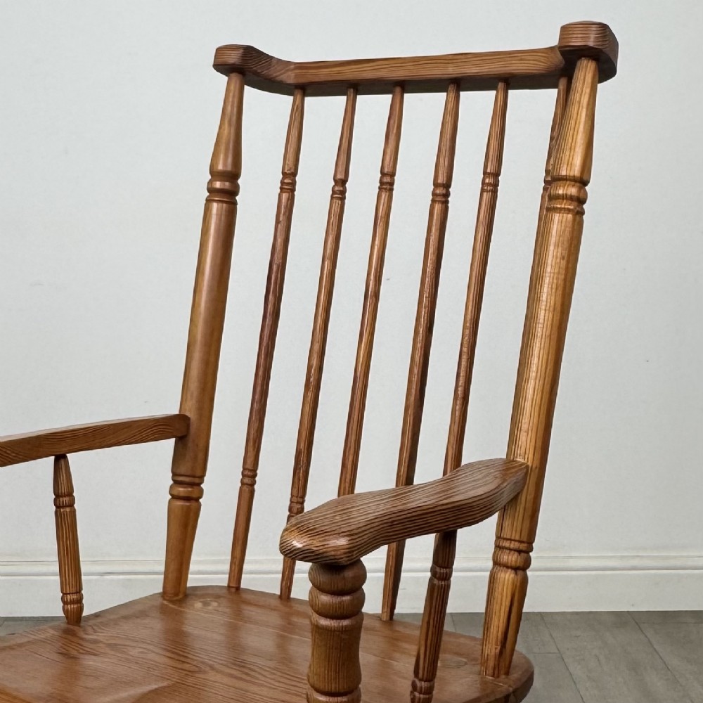 A twentieth-century pitch pine armchair featuring a tall stick back, sculpted armrests, and turned legs joined by stretchers. View X