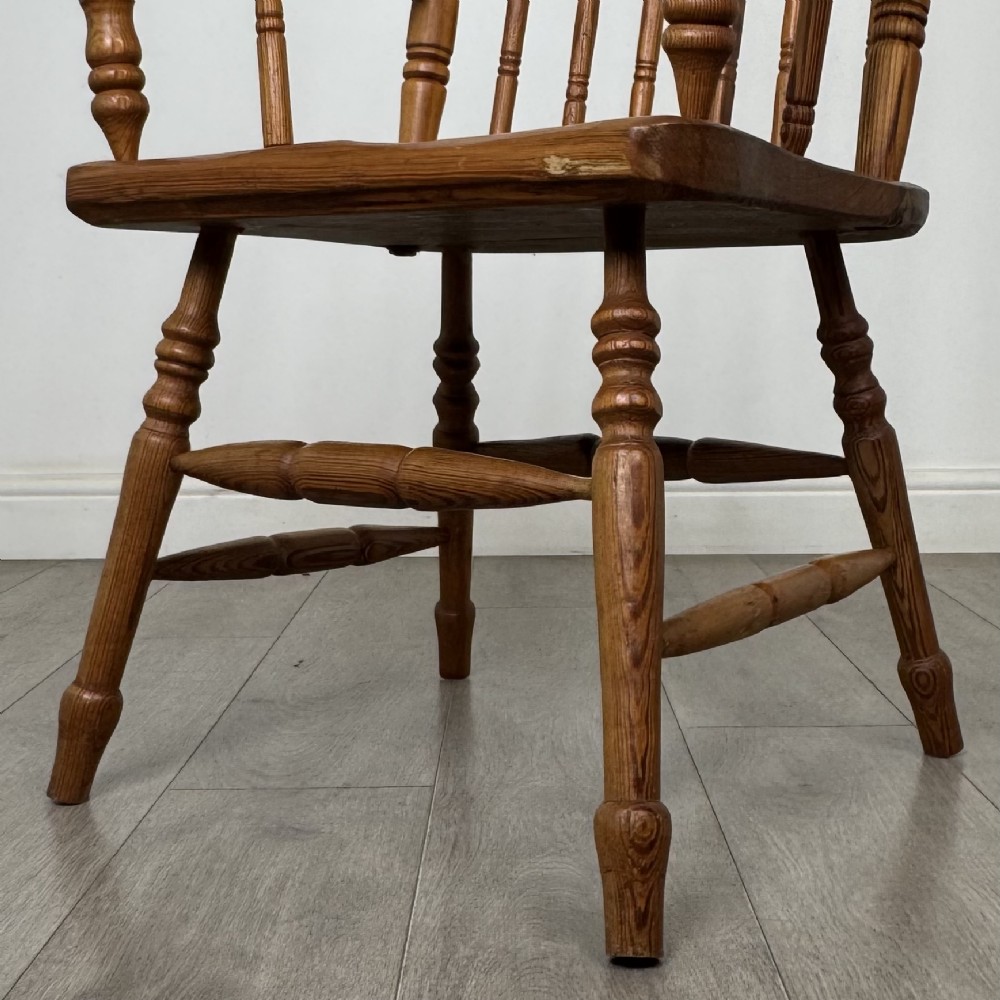 A twentieth-century pitch pine armchair featuring a tall stick back, sculpted armrests, and turned legs joined by stretchers. View XII