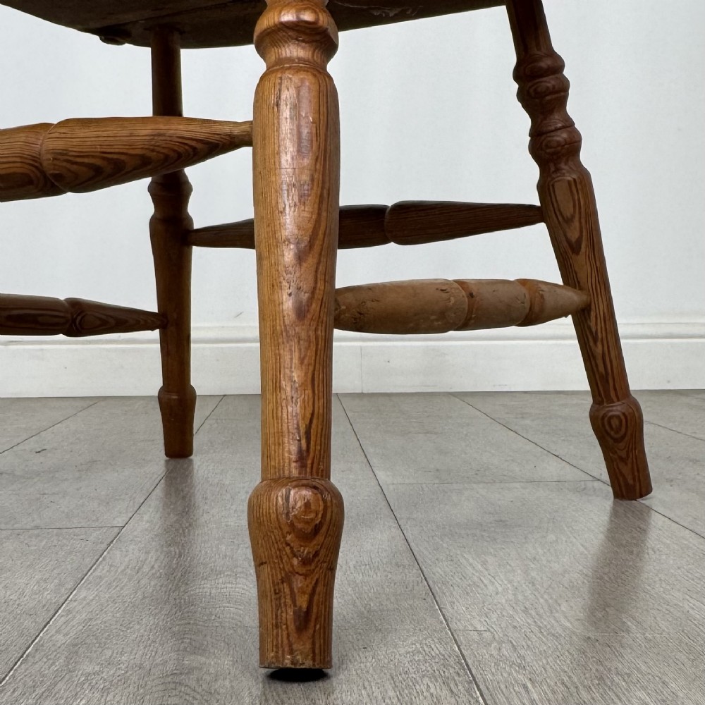 A twentieth-century pitch pine armchair featuring a tall stick back, sculpted armrests, and turned legs joined by stretchers. View XIII