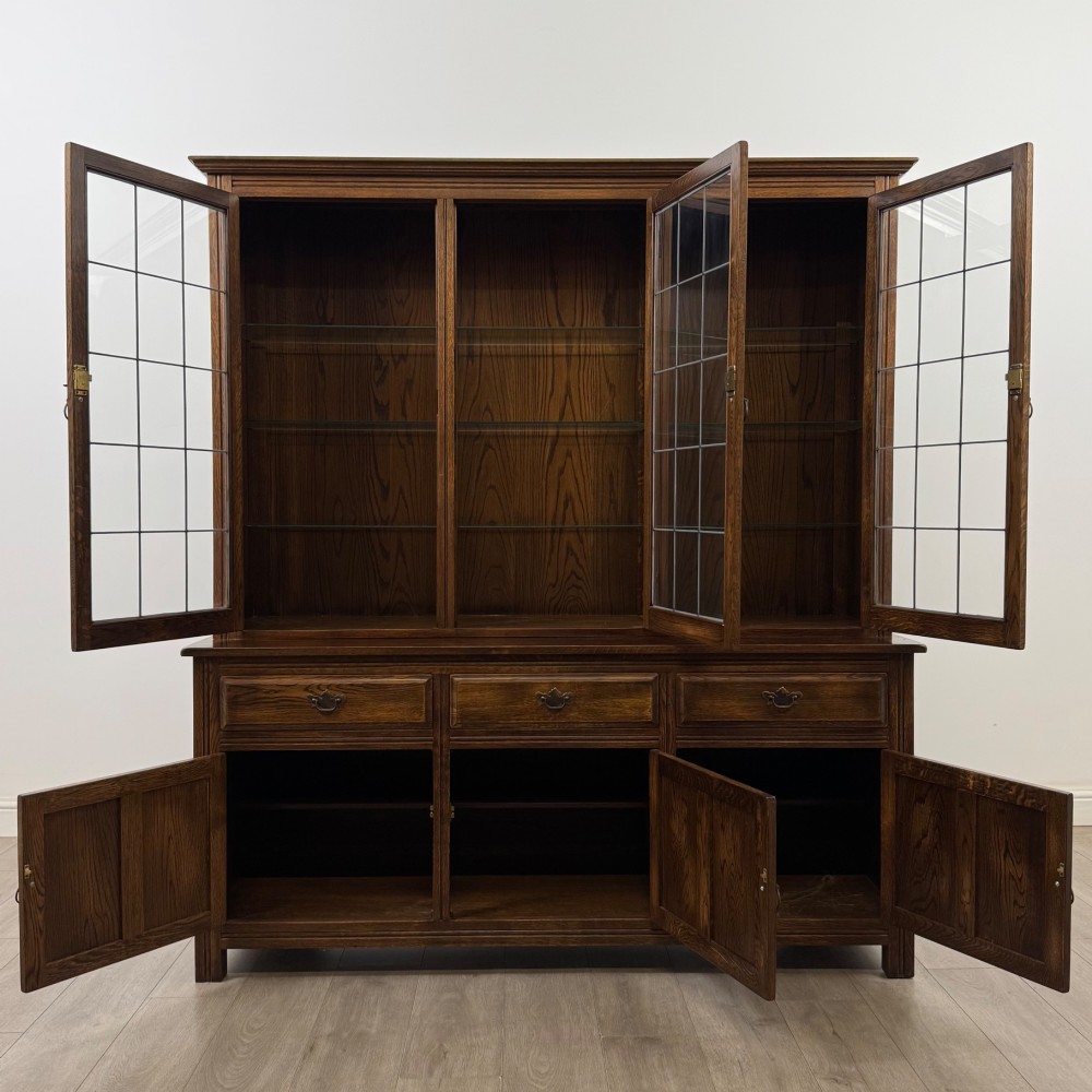 A large dark oak display cabinet featuring three leaded glass doors above three drawers and three panelled cupboard doors. View II