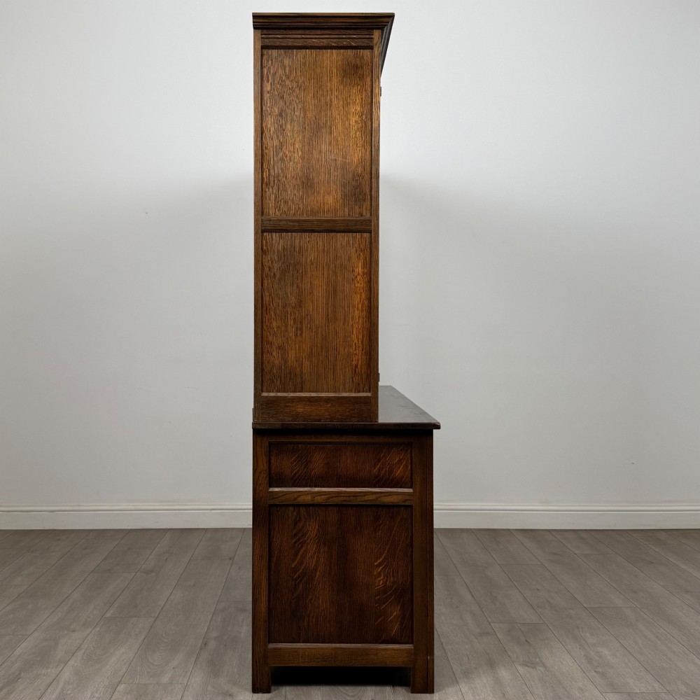 A large dark oak display cabinet featuring three leaded glass doors above three drawers and three panelled cupboard doors. View VIII