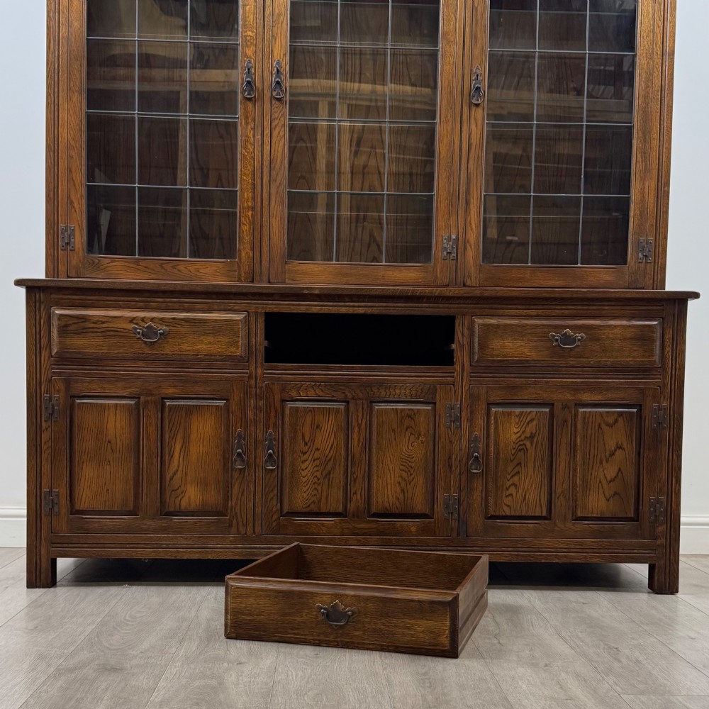 A large dark oak display cabinet featuring three leaded glass doors above three drawers and three panelled cupboard doors. View XI