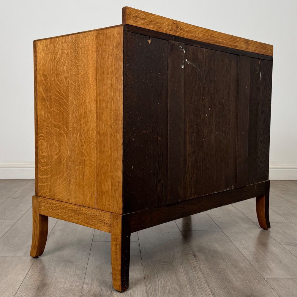 A golden oak chest of drawers featuring two short drawers over two long drawers with brass ring handles. View IV