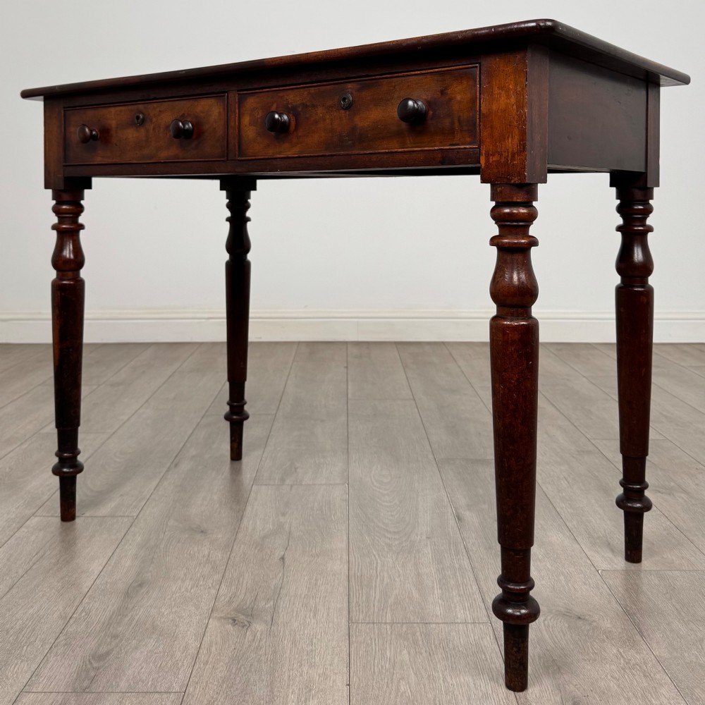 A Victorian dark mahogany writing table with two drawers, turned wooden knob handles, keyhole escutcheons, and four turned legs. View II