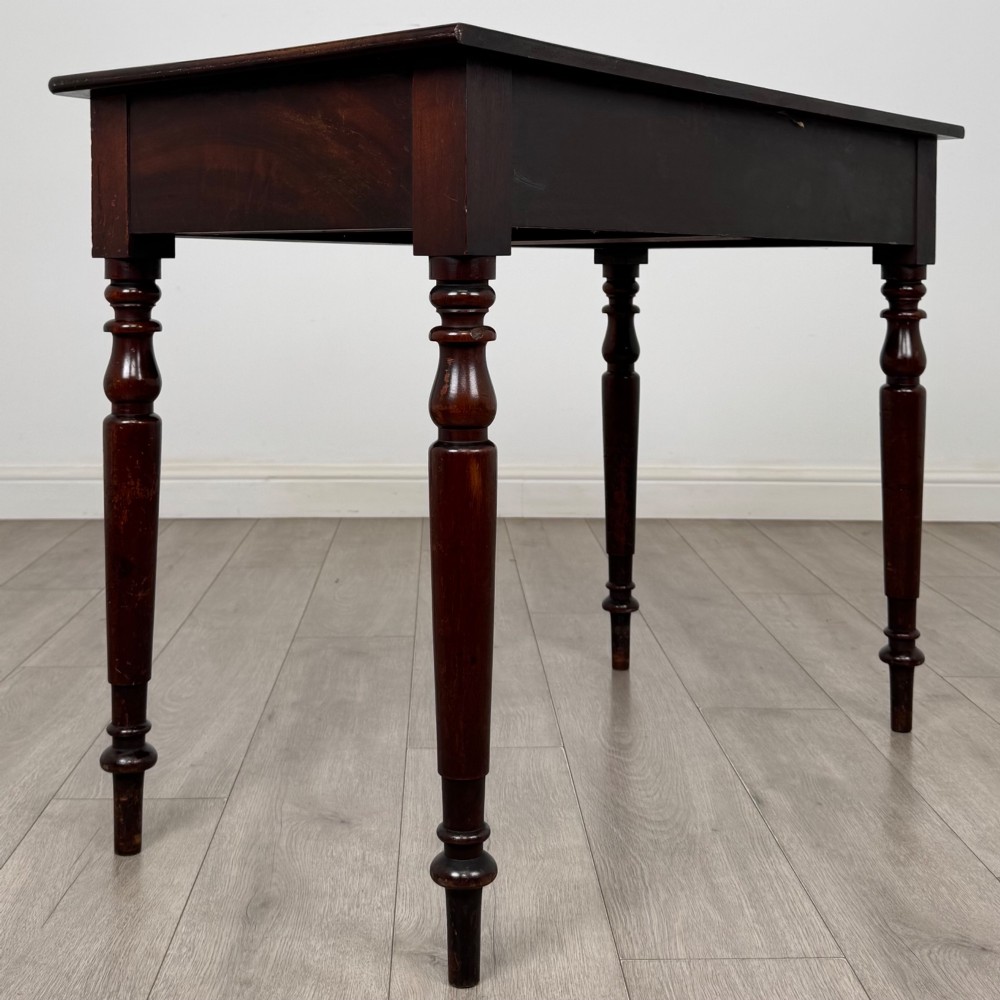 A Victorian dark mahogany writing table with two drawers, turned wooden knob handles, keyhole escutcheons, and four turned legs. View IV